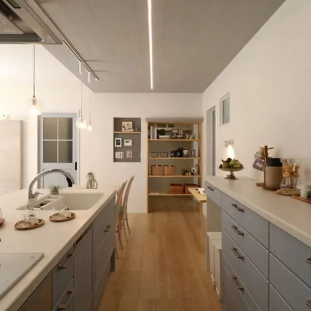 白を基調としたアイランドキッチンから奥の収納棚までつながる室内空間